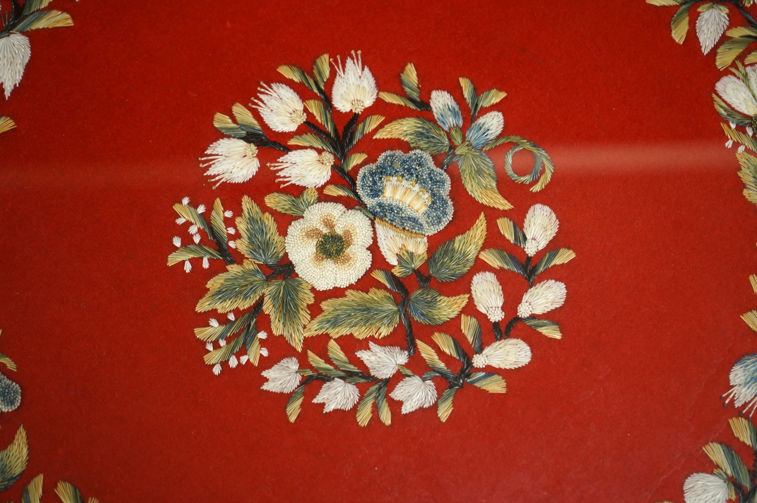 A framed, 19th century, possibly Scandinavian, red felt circular multi-coloured silk embroidery of flowers, acorns and leaves, also embroidered with fine stump work style beadwork flower detail, 32cm diameter. Condition